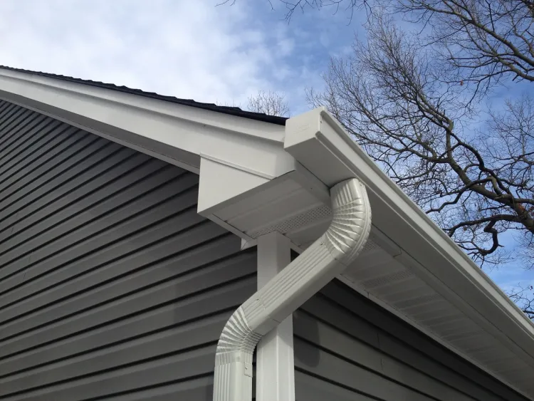 white gutter and downspout at the corner of the house
