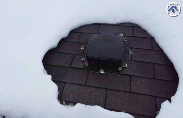 An exhaust vent surrounded by snow