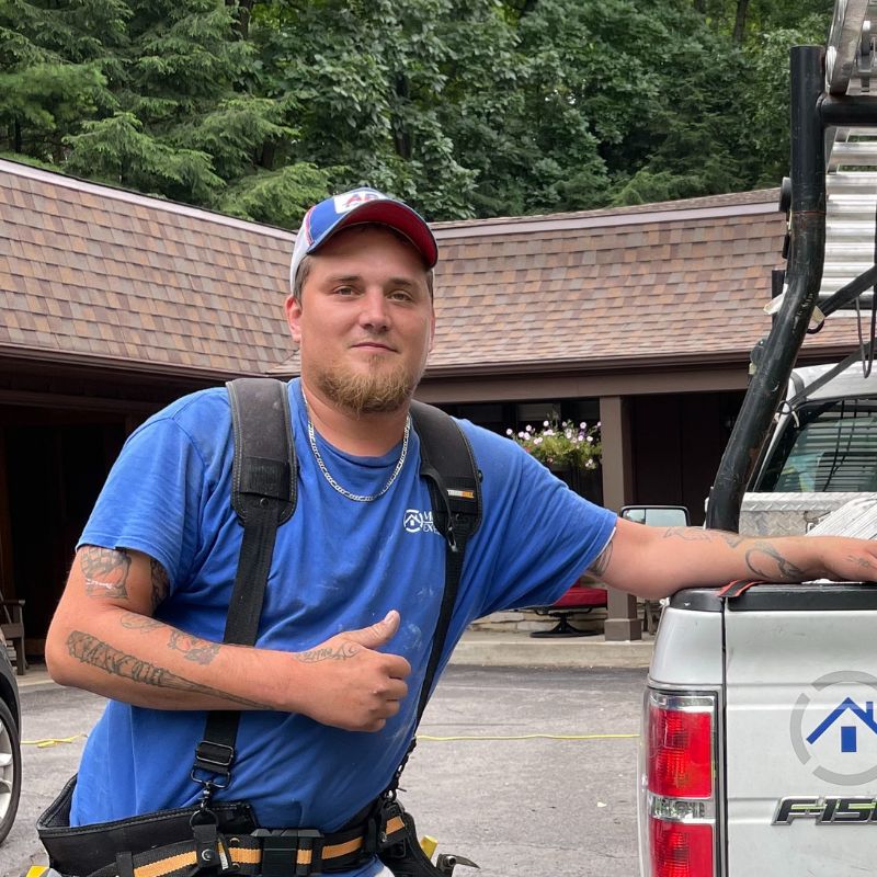 Exterior Employee giving thumbs up in front of shingles and truck