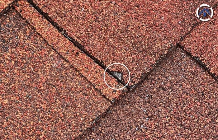Exposed fiber glass matting on an asphalt shingle roof
