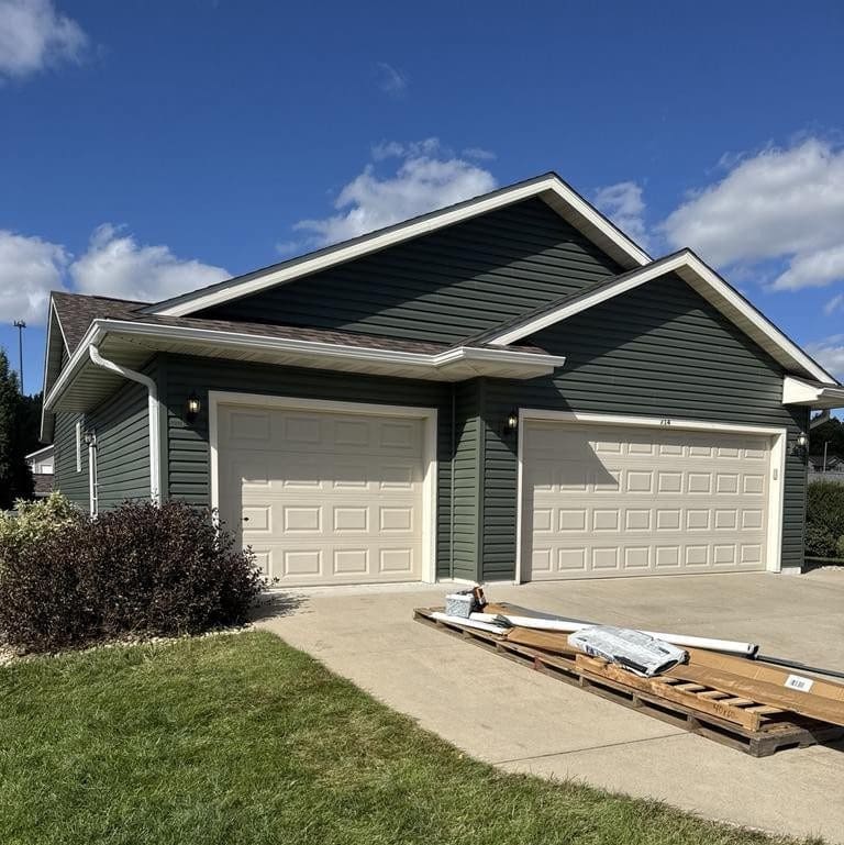 Completed exterior renovation on Evansville home featuring Spruce vinyl siding across house and garage, new roof, gutters, and downspouts by Modern Exterior