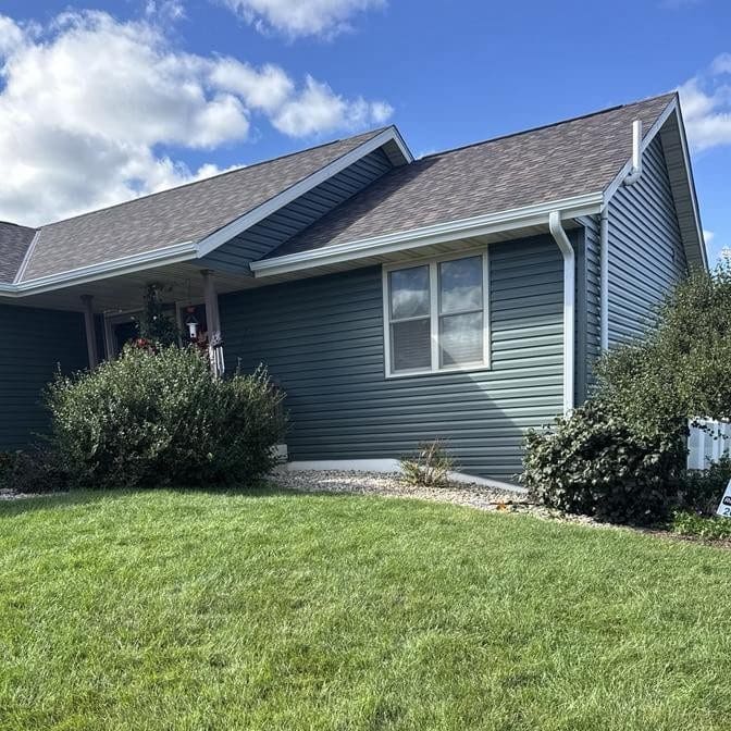Completed Evansville exterior renovation featuring vinyl siding in Spruce color across house and garage, with new roof and gutters installed by Modern Exterior