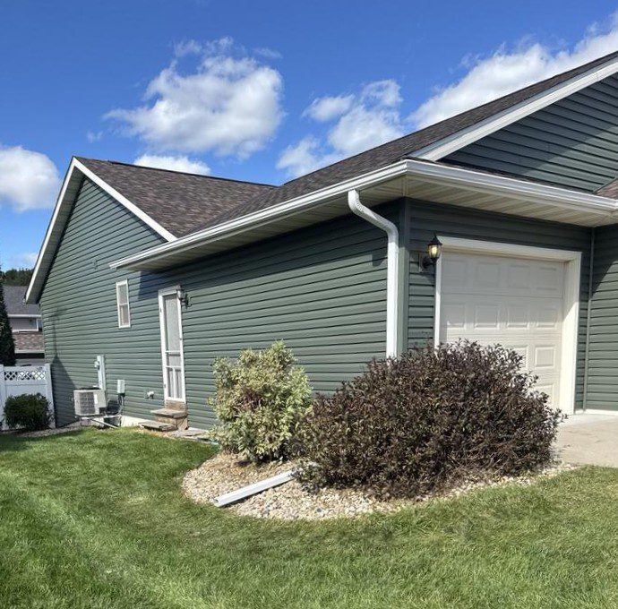 Completed Evansville exterior renovation featuring vinyl siding in Spruce color across house and garage, with new roof and gutters installed by Modern Exterior