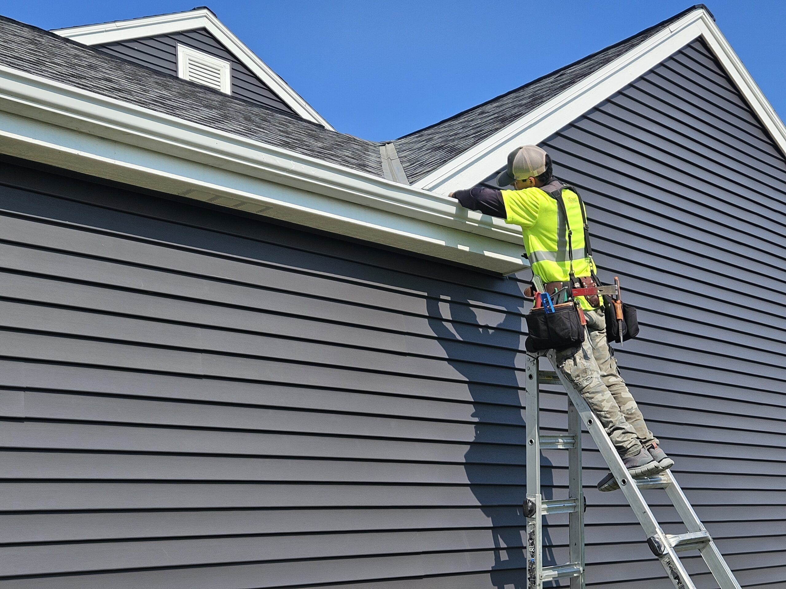 Modern Exterior worker installing gutter guards on a home to protect gutters from clogs and improve drainage.
