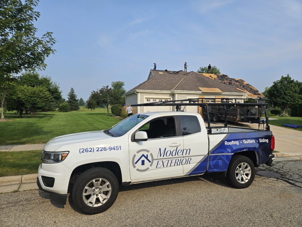 Modern Exterior crew replacing roof on a Middleton home with company truck in front, delivering professional roofing services.
