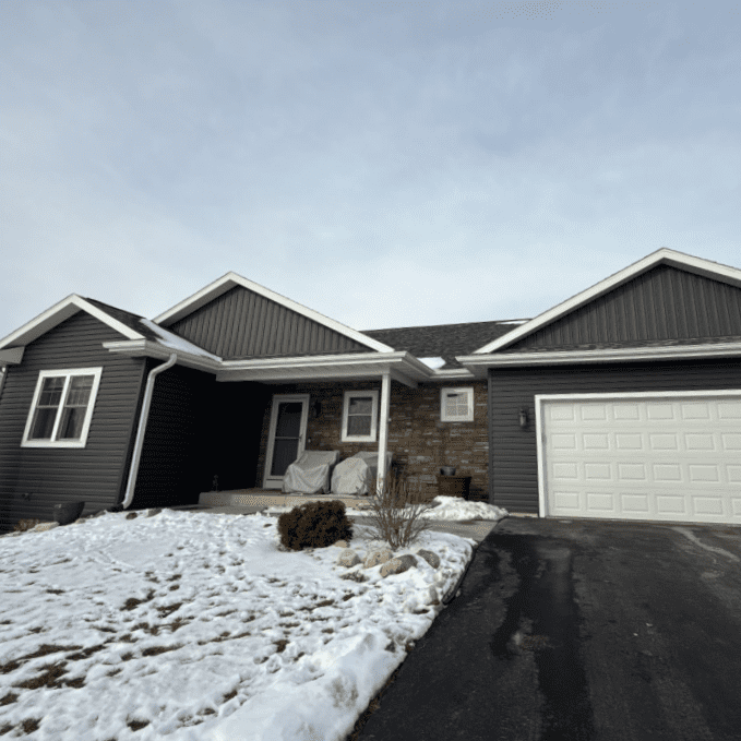 After photo of the front façade of an Oconomowoc, WI home featuring new Prem Pointe siding, Versetta Stone accents, board-and-batten gables, and updated trim completed by Modern Exterior.