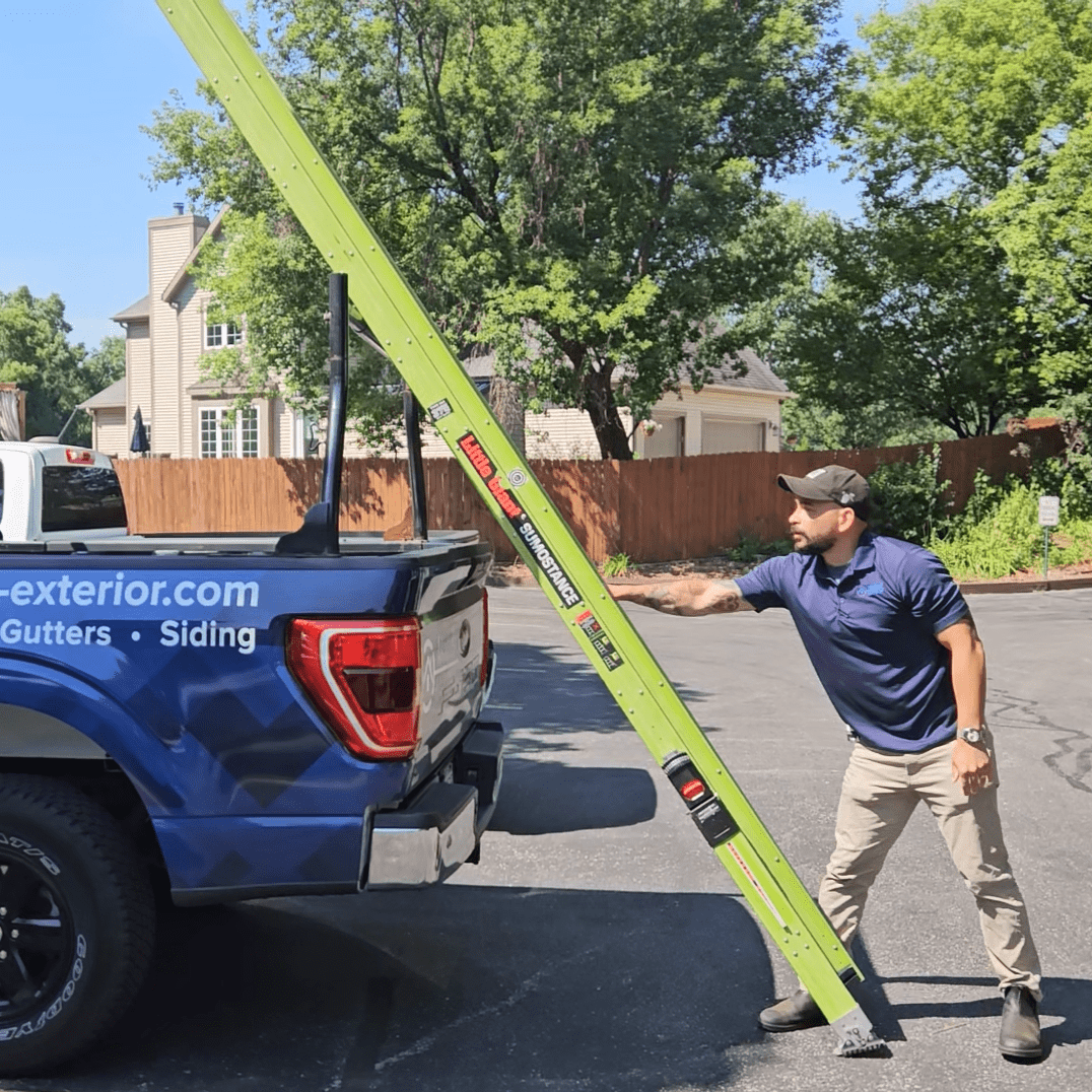 Modern Exterior technician unloading a ladder from company truck before a roof inspection.