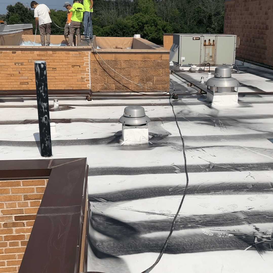 Modern Exterior crew installing flat commercial roofing system with welded seams and vent flashing on rooftop