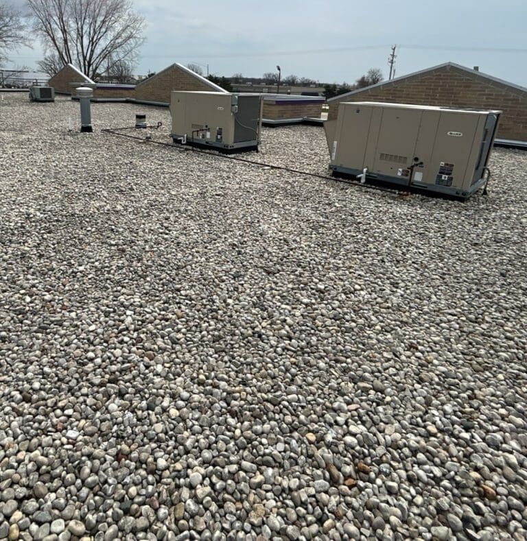Existing gravel-covered EPDM commercial roof at Central Bark Sussex with rooftop units before PVC roof replacement