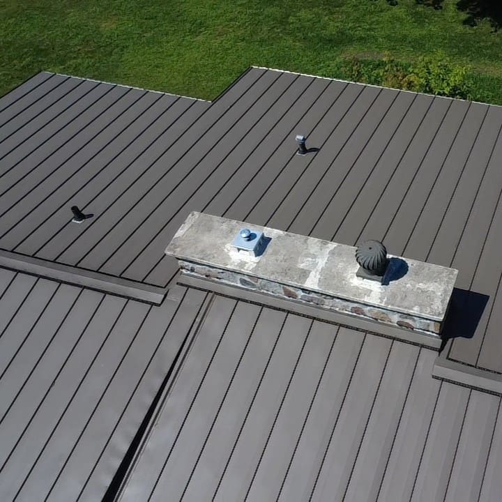 Standing seam metal roof with chimney flashing and vent penetrations properly sealed in Big Bend, Wisconsin.
