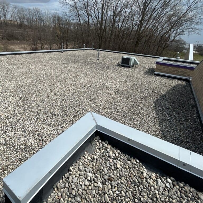 Before commercial roof replacement at Central Bark in Sussex showing gravel EPDM flat roof and existing metal coping prior to PVC installation