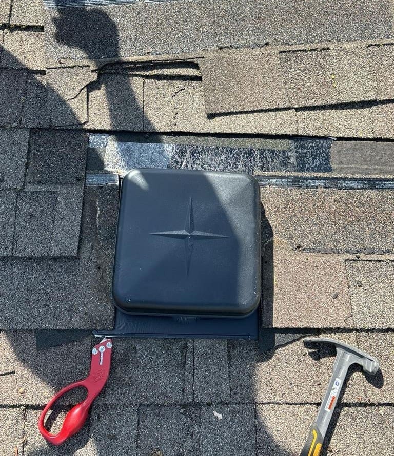 Roof repair in progress around a ventilation opening with flashing and sealing work being completed.